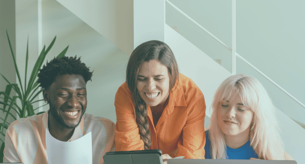 Three smiling individuals looking at a computer screen.