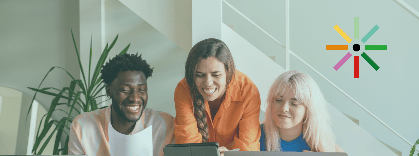 Three smiling individuals looking at a computer screen.